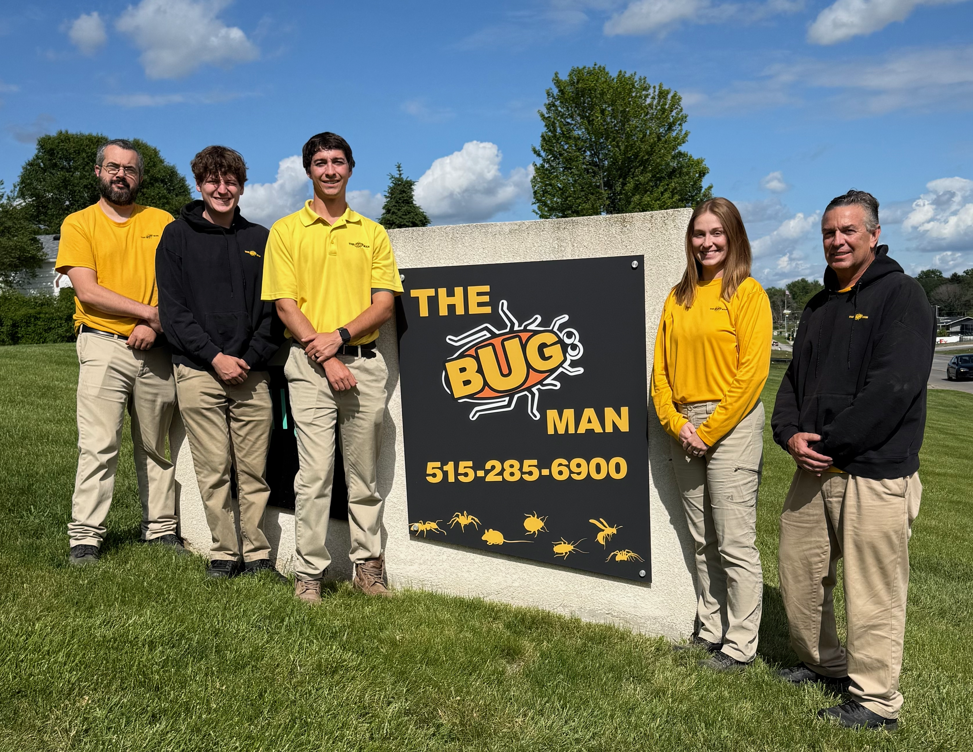 The Bug Man pest control team standing outside their Des Moines, Iowa office sign providing residential and commercial pest control services